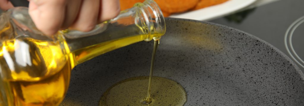 Woman adding oil on frying pan, closeup. Cooking breaded cutlets
